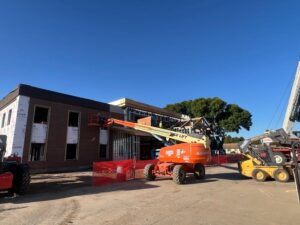 Image of bulldozer in front of branch working on window installation.