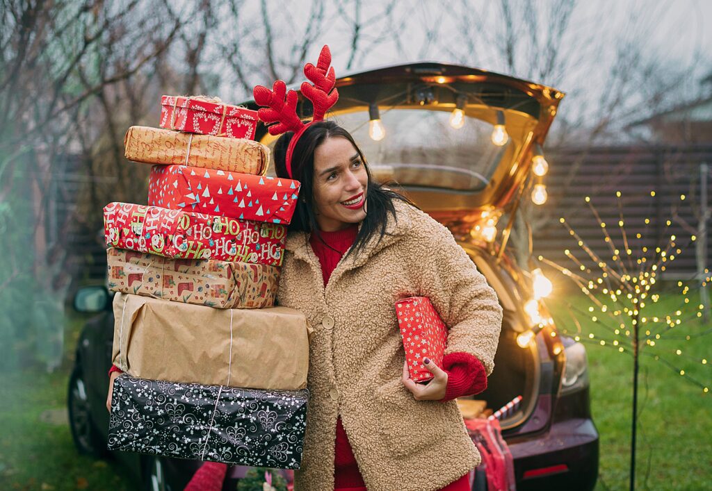 Woman holding stack of Christmas presents.