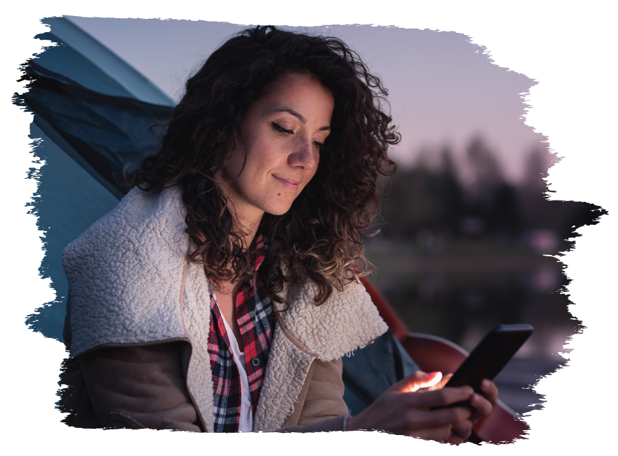 Young woman using a smartphone to access her mobile banking app while camping.