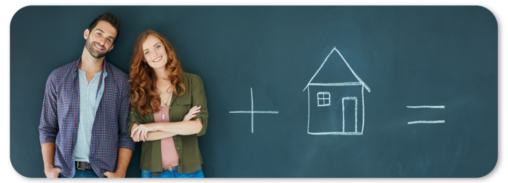 Couple standing in front of a chalkboard with chalk drawing of a house.